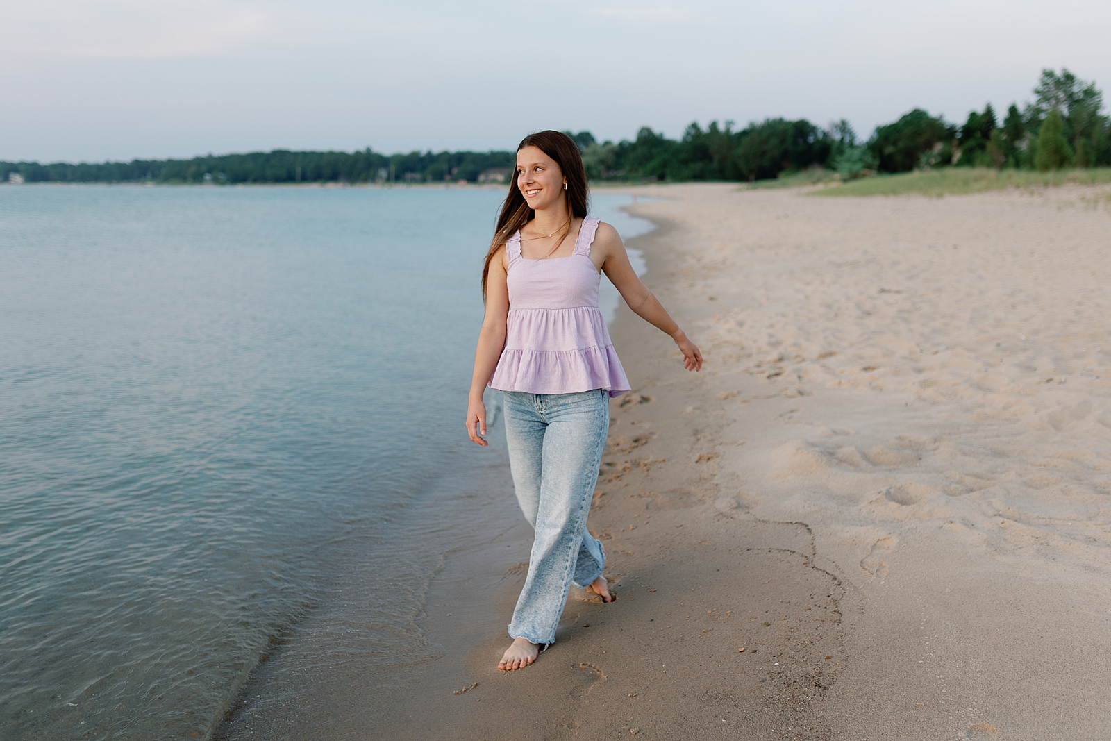 Beautiful girl walking alongside Lake Michigan during senior photo session in Elk Rapids